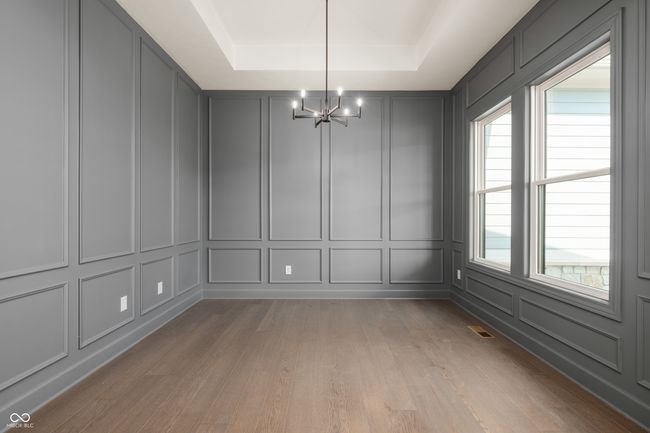Study featuring a raised ceiling, a decorative wall, light wood finished floors, and a chandelier. | Image 5