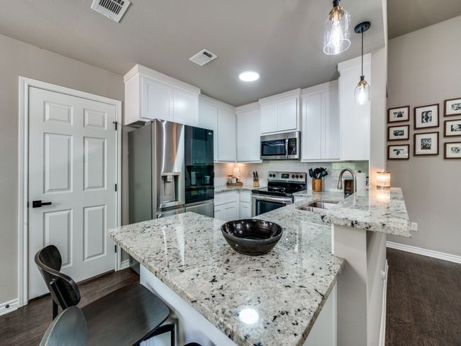 Kitchen featuring appliances with stainless steel finishes, a sink, a peninsula, baseboards, and a breakfast bar | Image 9