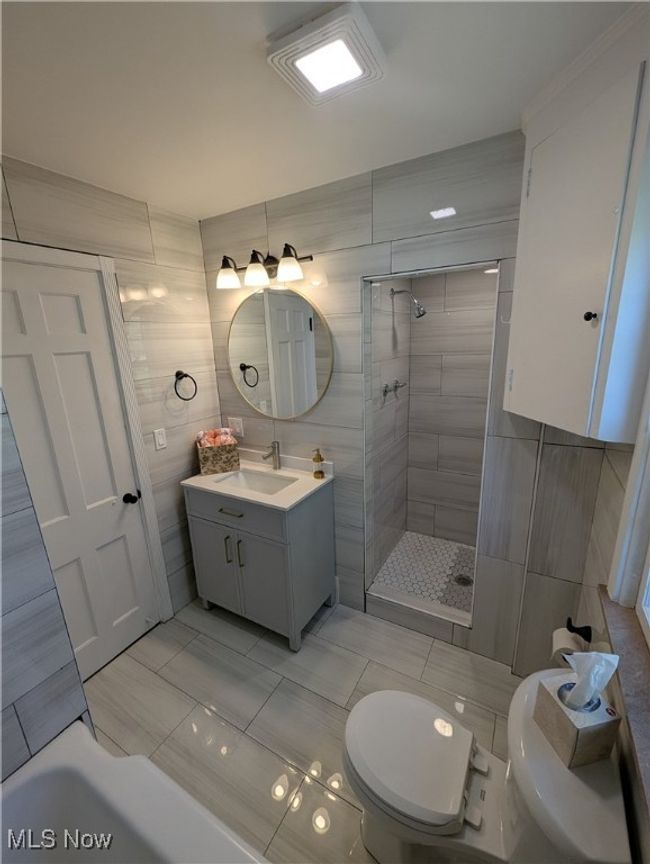 Bathroom with tile walls, a stall shower, and toilet | Image 6