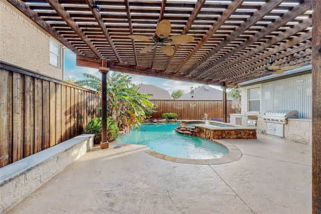 View of swimming pool with a ceiling fan, a fenced backyard, a pool with connected hot tub, a pergola, and a patio | Image 38
