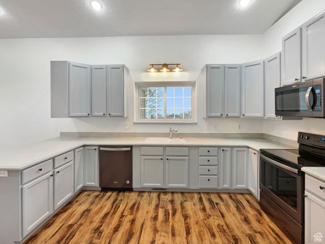 Kitchen with stainless steel appliances, a sink, wood finished floors, gray cabinets, and light countertops | Image 6