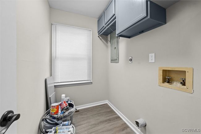 First Floor Washroom featuring cabinet space, hookup for an electric dryer, washer hookup, wood finished floors, and electric panel | Image 36