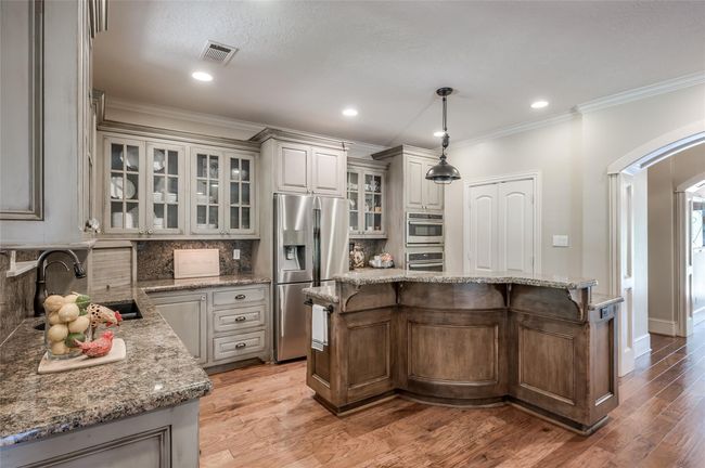 Custom-built kitchen cabinets with elegant paint and glaze finish, featuring unique curved molding on the center island. | Image 12