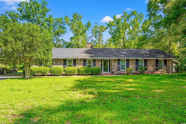 Ranch-style home featuring a front lawn, a chimney, brick siding, and a shingled roof | Image 21