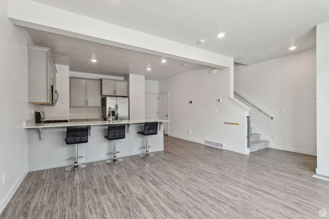 Kitchen featuring stainless steel appliances, LVP flooring, peninsula, with quartz countertops, and grey cabinetry | Image 7