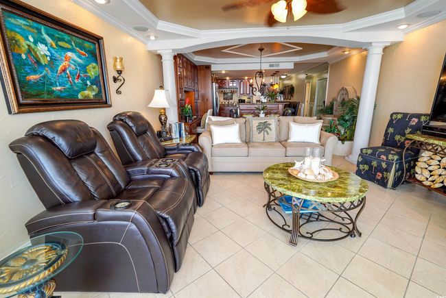 Living room featuring decorative columns, crown molding, light tile patterned floors, a chandelier, and ceiling fan | Image 6