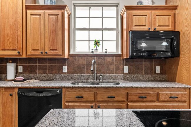 Kitchen featuring a sink, decorative backsplash, black appliances, and plenty of natural light | Image 13