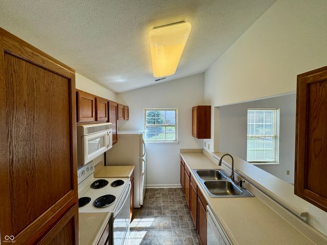 kitchen with a sink, white appliances, lofted ceiling, and light countertops | Image 5