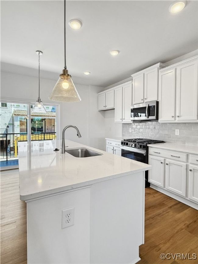 Kitchen with white cabinets, appliances with stainless steel finishes, decorative backsplash, and a sink | Image 7