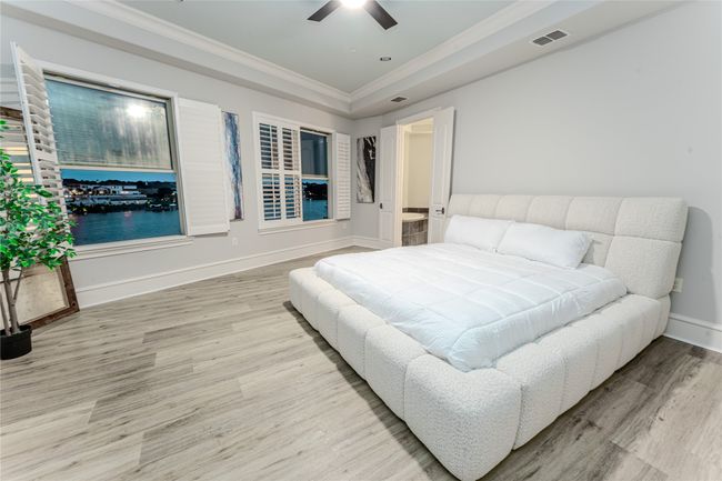 Bedroom with wood finished floors, crown molding, a tray ceiling, and a ceiling fan | Image 22