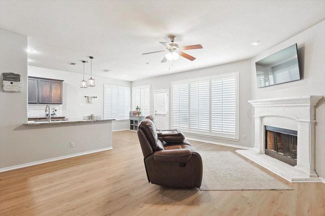 Living room featuring ceiling fan, light wood finished floors, a fireplace with raised hearth, and recessed lighting | Image 9