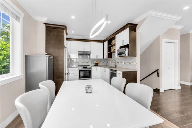 Kitchen with appliances with stainless steel finishes, under cabinet range hood, open shelves, light countertops, and crown molding | Image 6