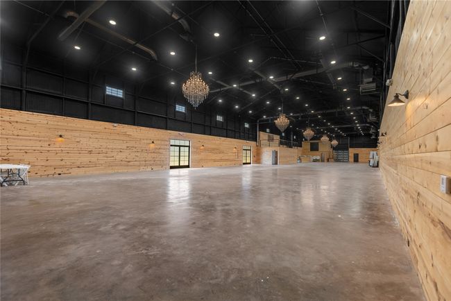 Main event area with a high ceiling, wood walls, finished concrete flooring, and a chandelier | Image 11