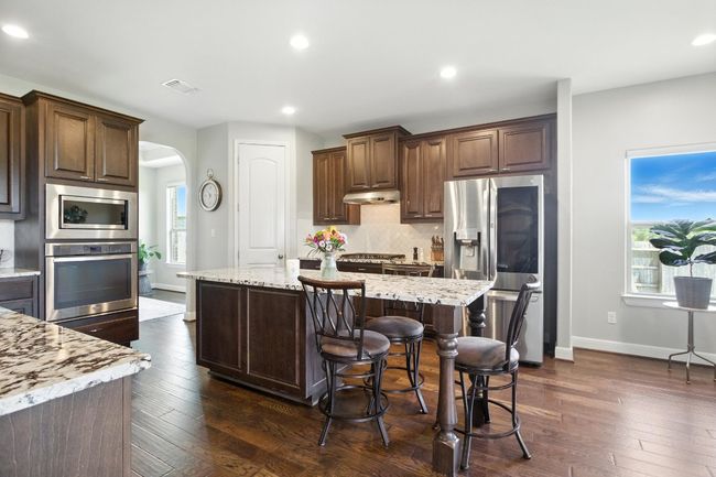 Kitchen featuring appliances with stainless steel finishes, arched walkways, under cabinet range hood, backsplash, and plenty of natural light | Image 4