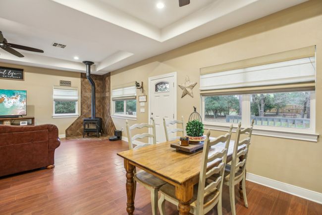 Dining room featuring hardwood / wood-style flooring, a raised ceiling, ceiling fan, and a wood stove | Image 12