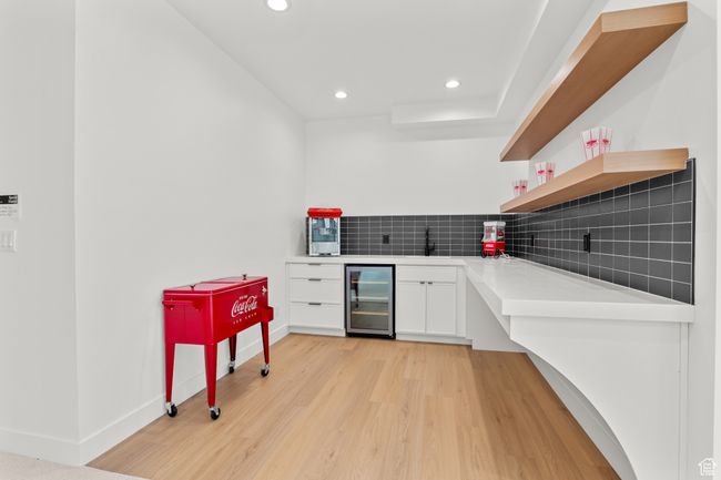 Kitchen featuring tasteful backsplash, light wood-style flooring, wine cooler, recessed lighting, and white cabinets | Image 5