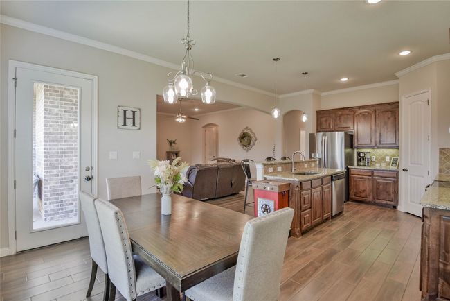 Dining room featuring arched walkways, wood finished floors, ornamental molding, and recessed lighting | Image 16