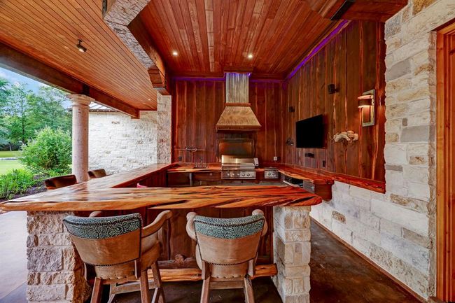 The outdoor kitchen has beautiful cedar countertops with turquoise inlay, sink, and a gas grill. | Image 40