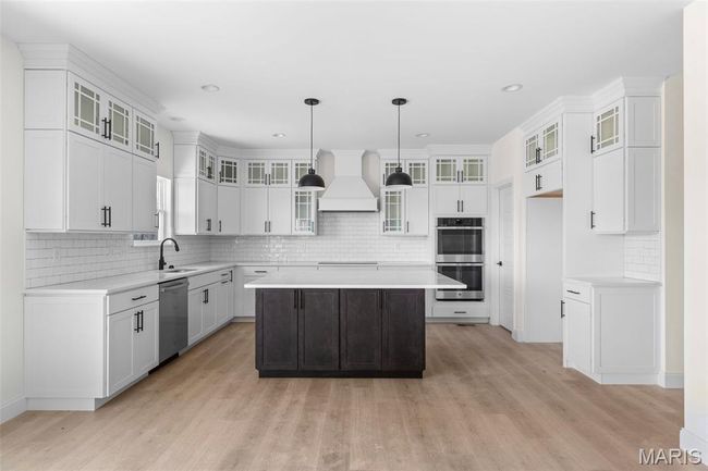 Kitchen featuring stainless steel appliances, custom exhaust hood, light wood-style floors, tasteful backsplash, and recessed lighting | Image 18