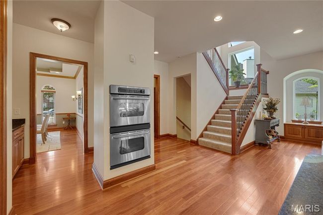 Kitchen with stainless steel double oven, light wood-type flooring, recessed lighting, and arched walkways | Image 19
