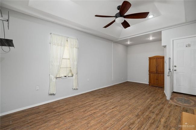 Unfurnished room with hardwood / wood-style floors, a raised ceiling, and ceiling fan | Image 10