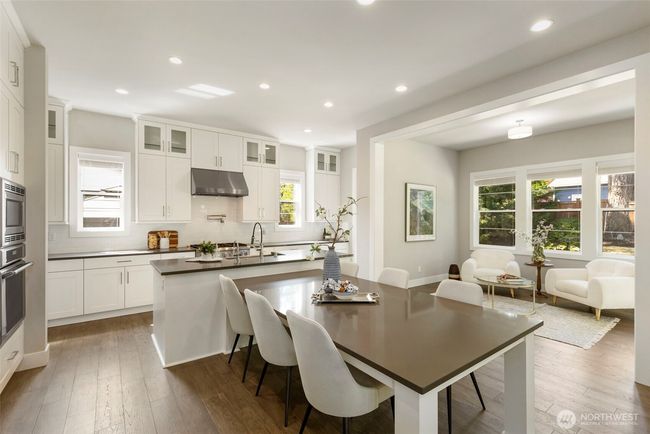 Anchoring the home with style and function, this modern kitchen boasts an oversized island with seating, quartz countertops, and a professional-grade range with a statement hood. Bathed in natural light and open to a charming sitting area, it’s perfectly designed for both daily living and elegant entertaining. | Image 12