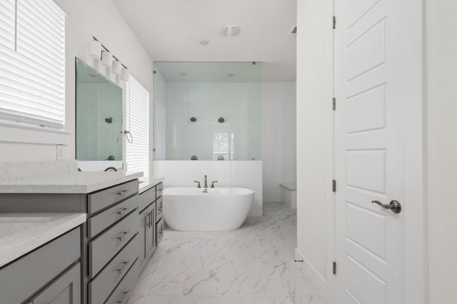 Bathroom featuring marble look tile flooring, a walk in shower, a freestanding tub, and vanity | Image 20