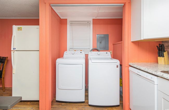 Laundry room featuring electric panel, washer and dryer, wood finished floors, wood walls, and crown molding | Image 14