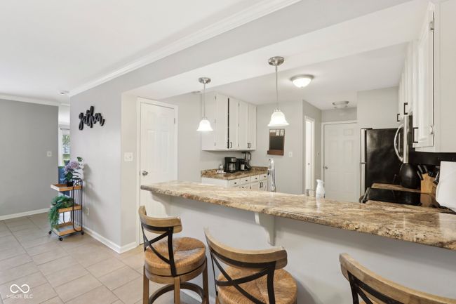 kitchen featuring decorative light fixtures, baseboards, white cabinetry, and light tile patterned floors | Image 9