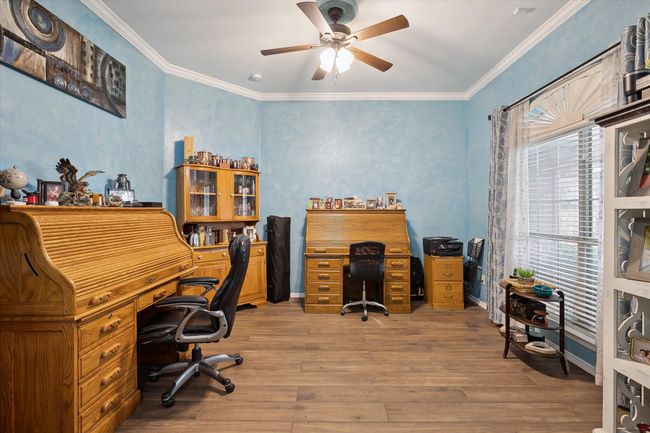 Home office with ceiling fan, wood finished floors, crown molding, and baseboards | Image 15