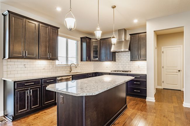 kitchen with wall chimney range hood, appliances with stainless steel finishes, hardwood / wood-style flooring, and a sink | Image 18