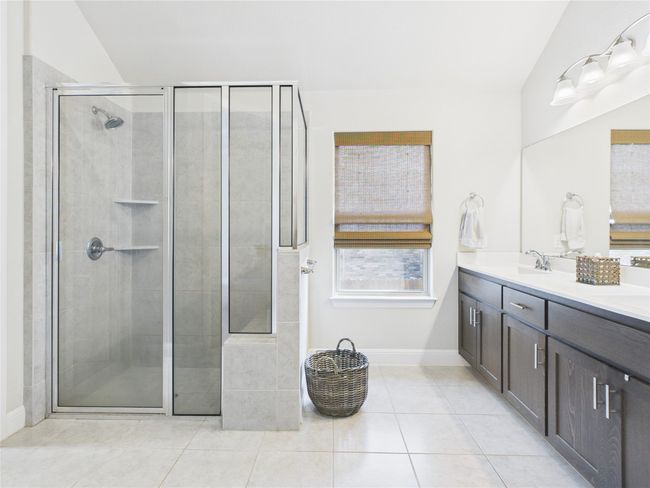 Full bath with baseboards, double vanity, tile patterned floors, a sink, and a stall shower | Image 14