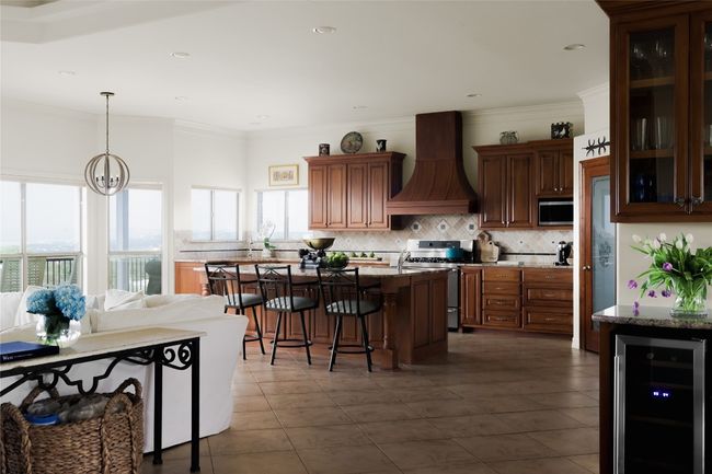 Kitchen with custom exhaust hood, appliances with stainless steel finishes, wine cooler, decorative backsplash, and ornamental molding | Image 18