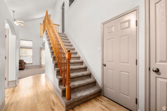 Staircase with arched walkways, wood finished floors, a ceiling fan, a towering ceiling, and baseboards | Image 6