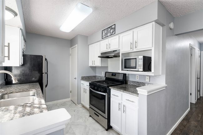 Kitchen featuring sink and stainless steel appliances, and white cabinets | Image 14