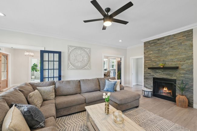 Living area with ornamental molding, recessed lighting, ceiling fan, a fireplace, and wood finished floors | Image 6