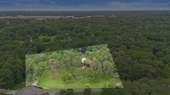 Aerial view highlighting the property within the wooded area. | Image 43