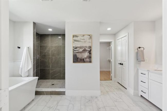 The spa-like primary bathroom, featuring a luxurious soaking tub, seperate shower, double vanities, and a spacious walk-in closet. | Image 18