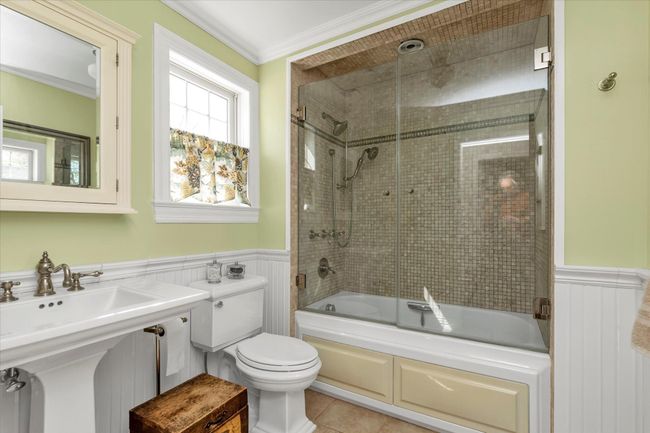 Bathroom with shower / bath combination with glass door, crown molding, toilet, and wainscoting | Image 11