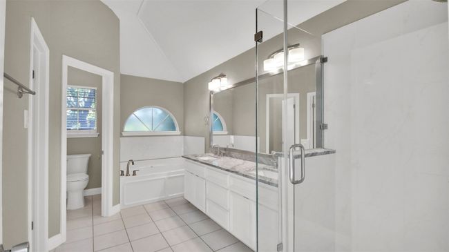 Primary bathroom with lofted ceiling, toilet, tile patterned floors, a garden tub, and vanity | Image 14