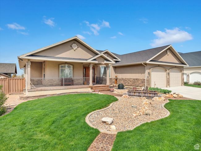 View of front of home with driveway, covered porch, a front yard, a garage, and stucco siding | Image 39