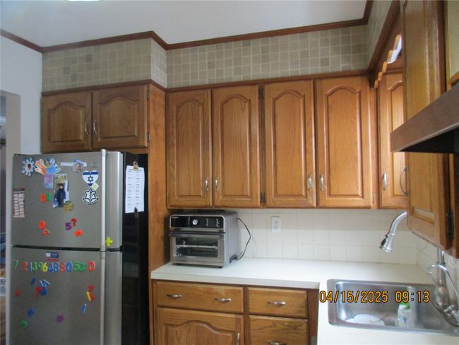 Kitchen featuring brown cabinets, tasteful backsplash, light countertops, and freestanding refrigerator | Image 9