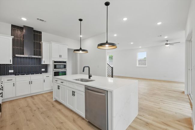 Kitchen with stainless steel appliances, a sink, wall chimney range hood, light wood-type flooring, and recessed lighting | Image 17