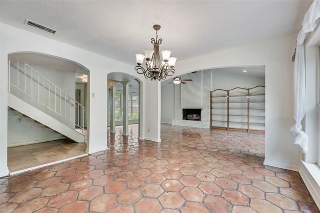 Unfurnished living room featuring arched walkways, a fireplace, a chandelier, stone finish flooring, and recessed lighting | Image 8