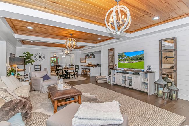Living room with a chandelier, wood ceiling, dark wood-type flooring, wooden walls, and healthy amount of natural light | Image 4