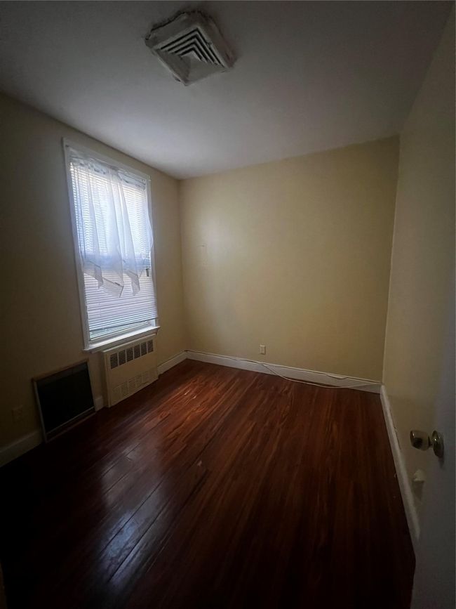 Spare room with radiator, dark wood finished floors, and baseboards | Image 5