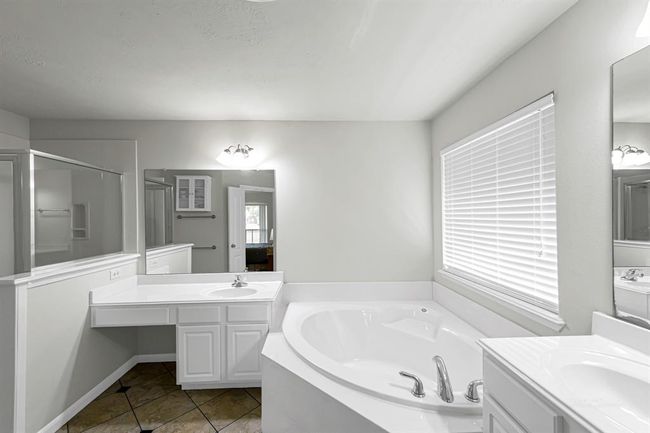 Primary bath features a corner garden tub, separate shower and dual vanities and a walk-in closet. | Image 14