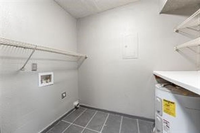 Washroom featuring electric dryer hookup, washer hookup, water heater, and dark tile patterned flooring | Image 23