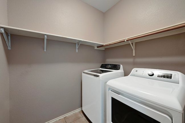 Laundry area featuring washer and dryer and light tile patterned flooring | Image 16