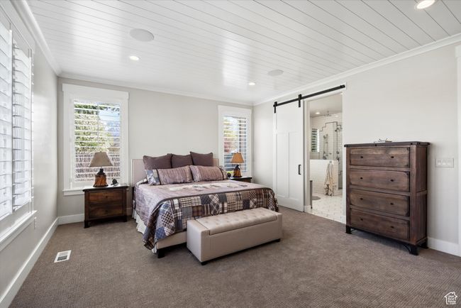 Carpeted bedroom featuring ornamental molding, visible vents, recessed lighting, and a barn door | Image 24